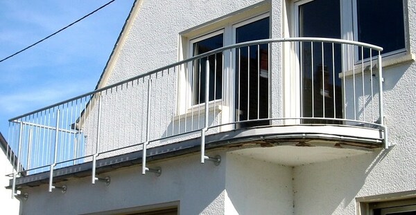 Moderner Balkon mit weißem Geländer an einem Einfamilienhaus mit Putzfassade.